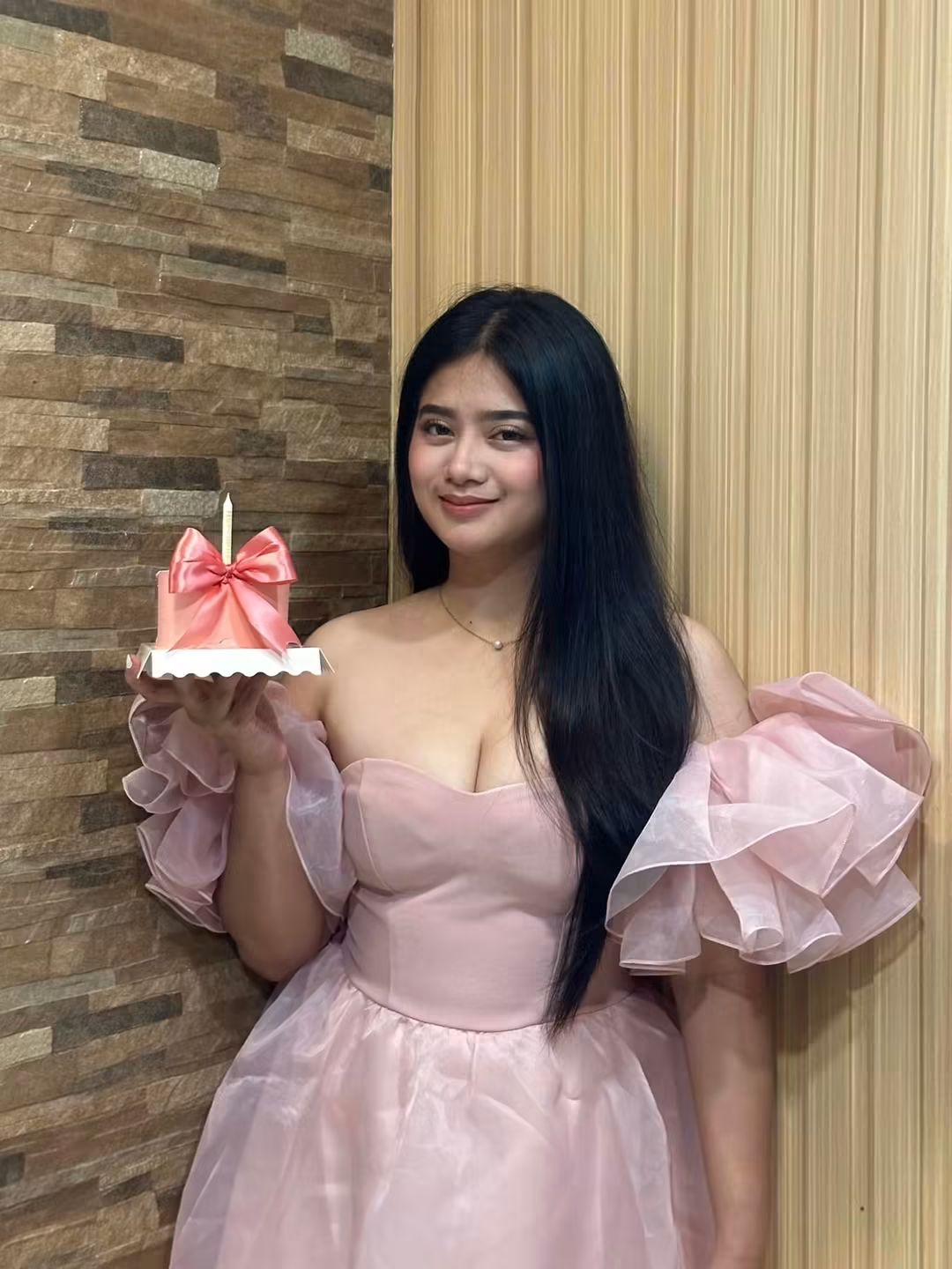 Tala in a pink dress holding a cake